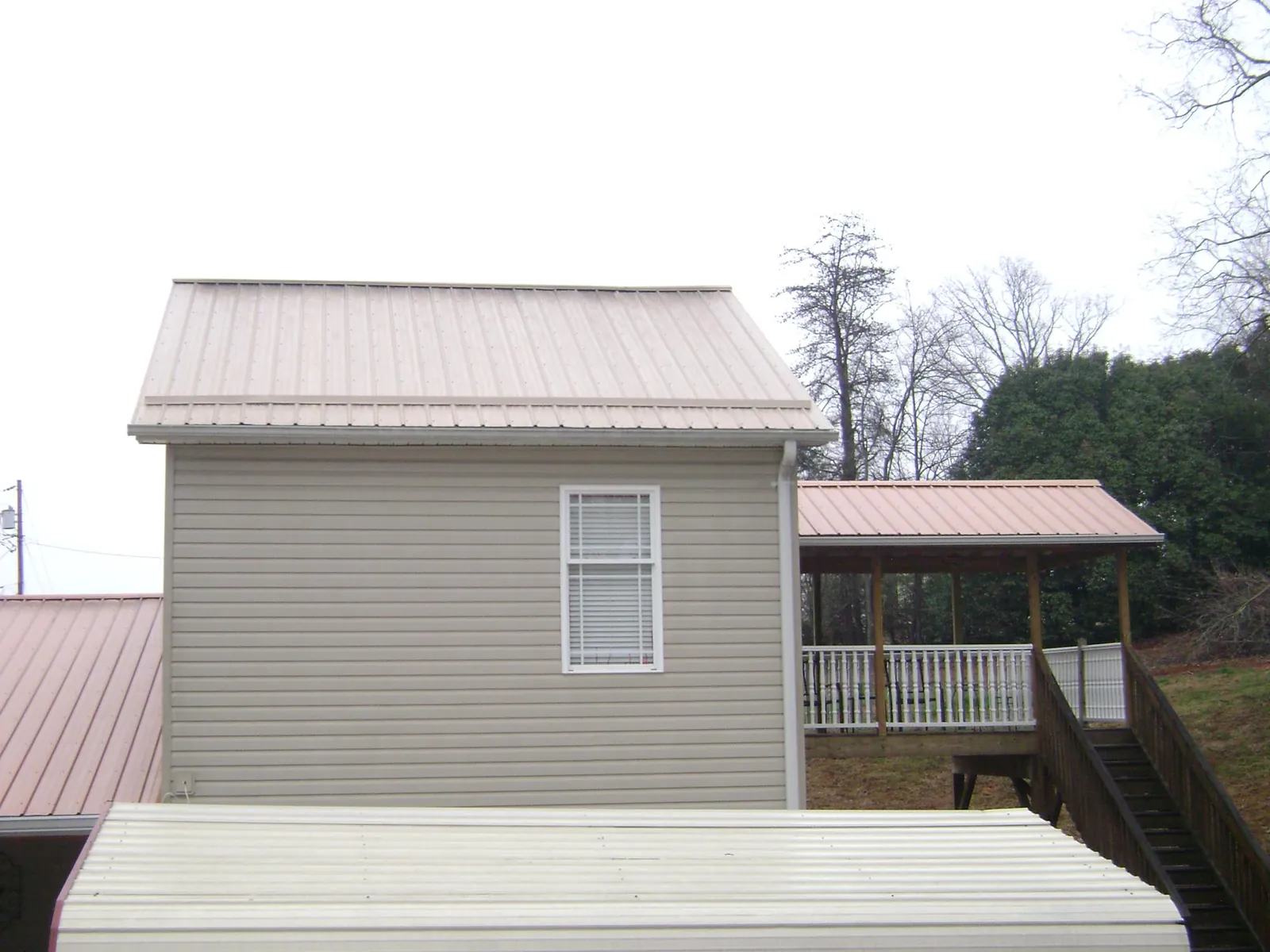 Tan metal roofs on a two story addition and attached porch, from a Roof Replacement job in Fremont